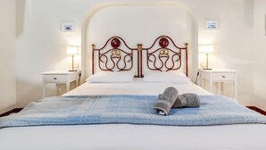 A bed with a red headboard, white bedding, two bedside tables with lamps, and a blue blanket on the bed.