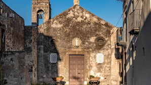 A historic church with a bell tower, cobblestone path, and a small garden area.
