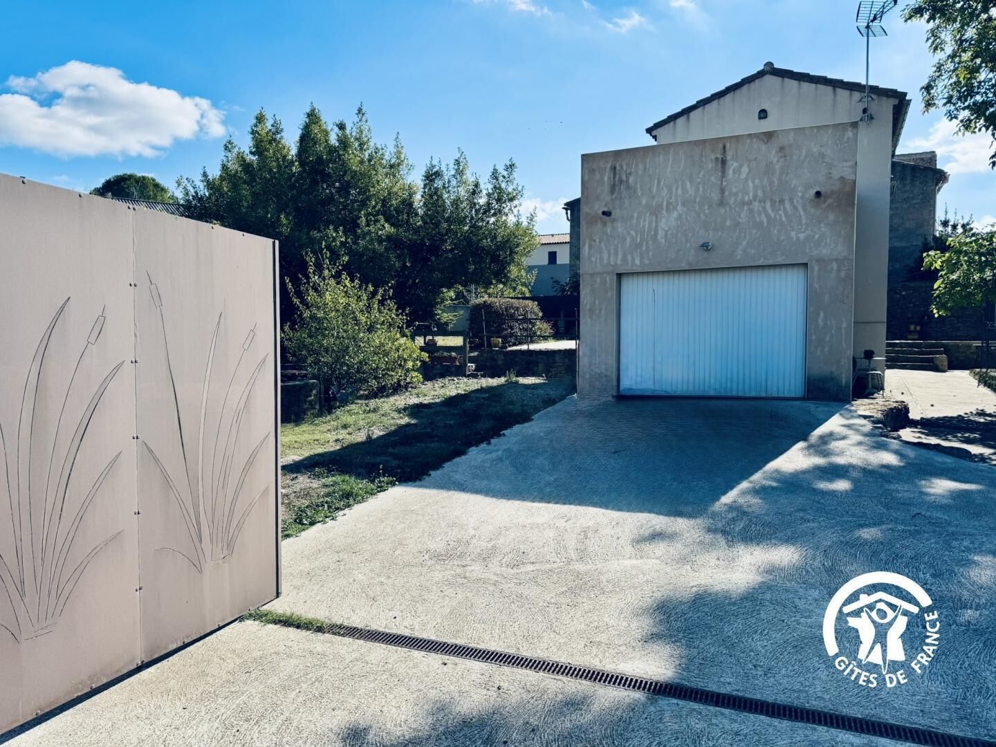 En moderne bygning med garageport, en støbt sti og et hegn med plantemotiver.