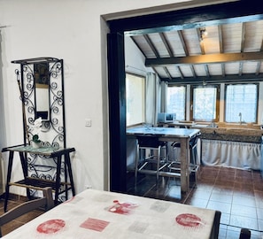 A kitchen with a wooden ceiling, a dining area with a table and chairs, and a decorative mirror. - Le Jardin de Marie - TALAIRAN (TALAIRAN)