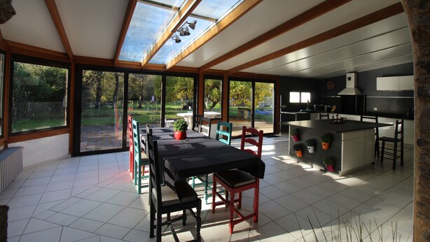 Een moderne keuken met grote ramen, een eethoek met tafel en stoelen, en uitzicht op de omgeving.