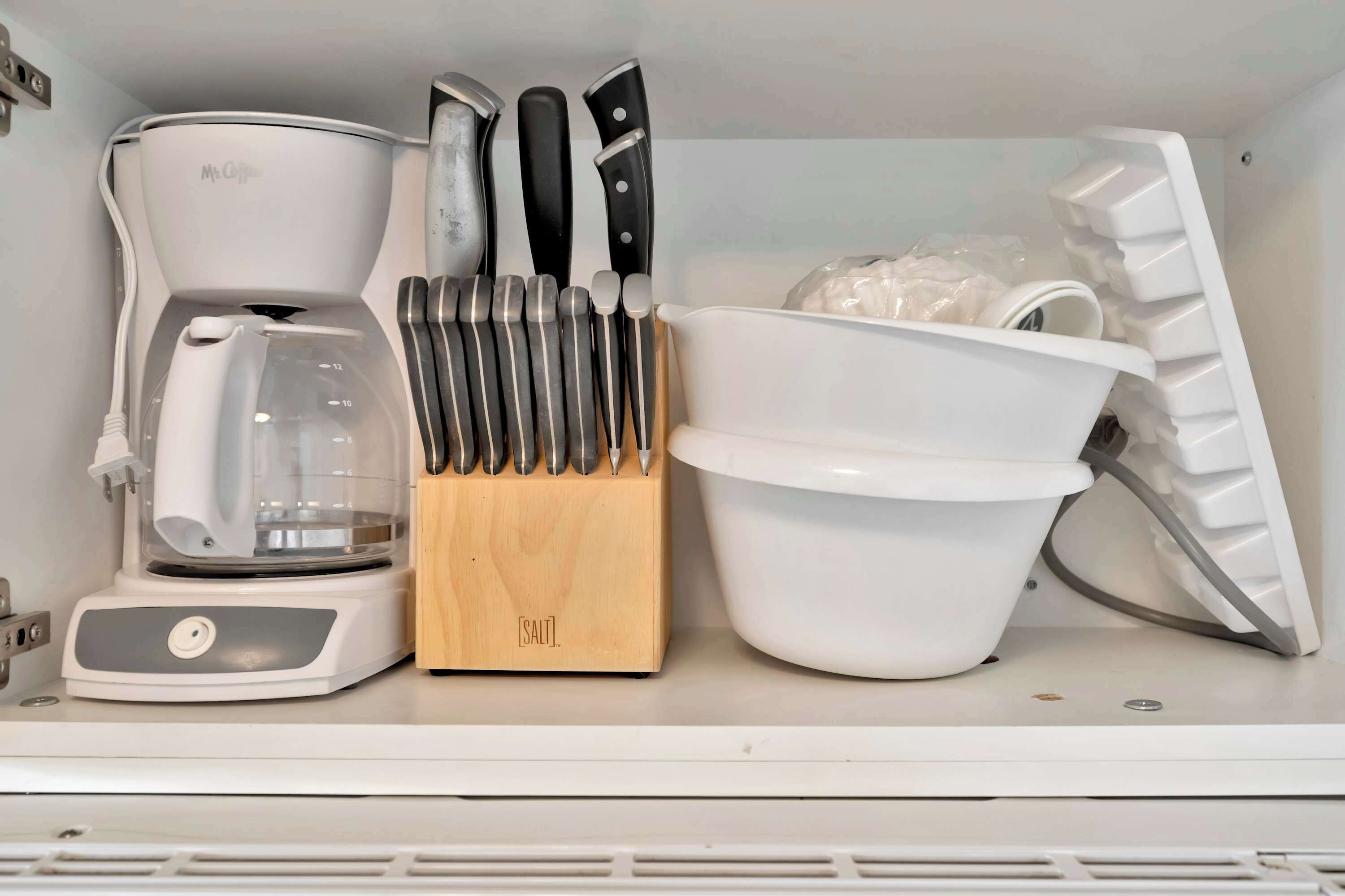 A kitchen with a coffee maker, knife block, and a white bowl.