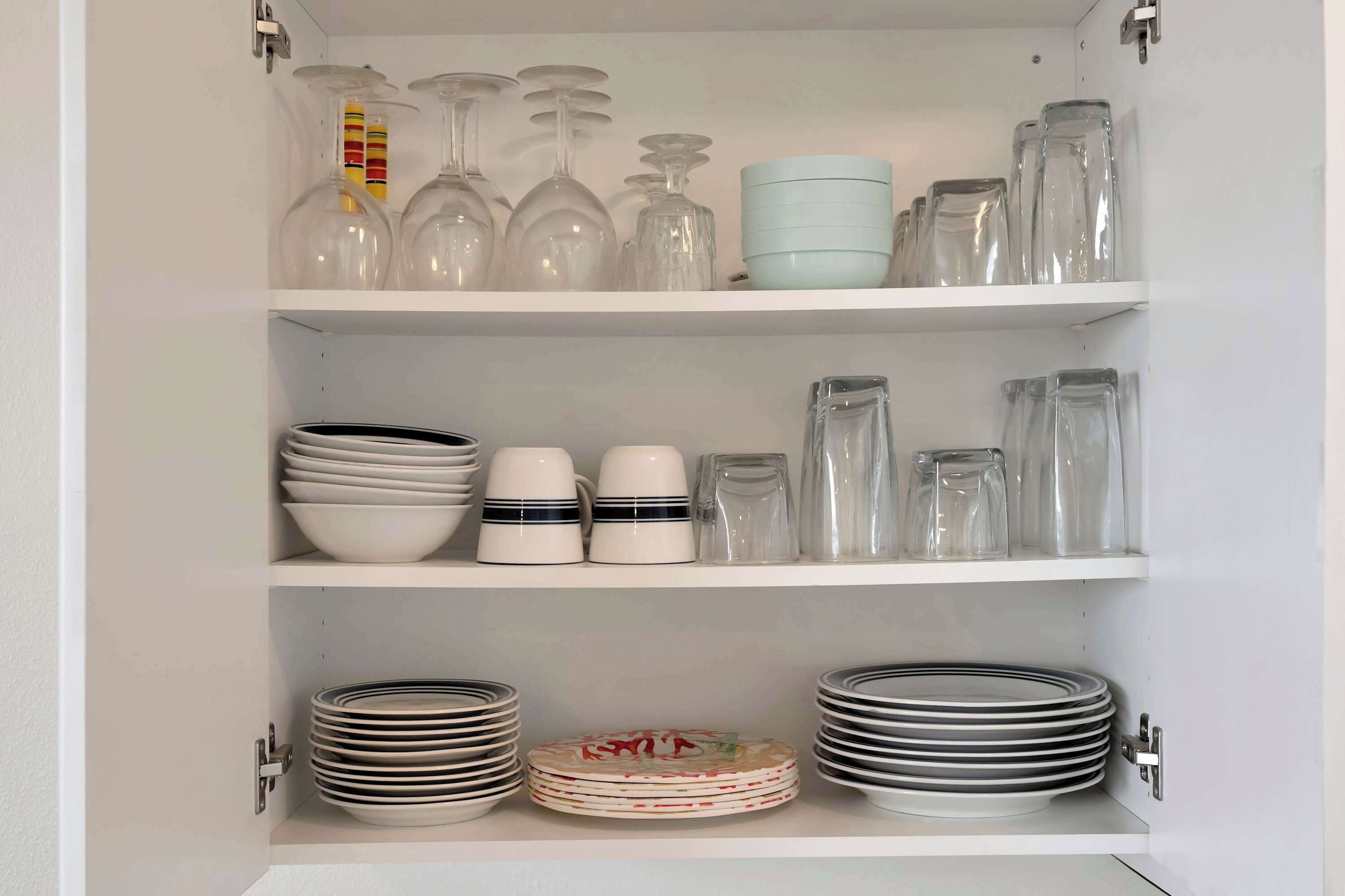 Un meuble de cuisine doté d’étagères contenant divers articles en verre, assiettes et bols.