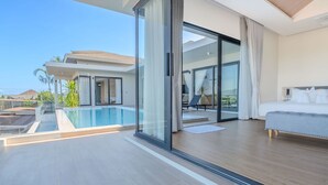 Quarto de hotel moderno com uma grande porta de vidro que dá para uma varanda com piscina.