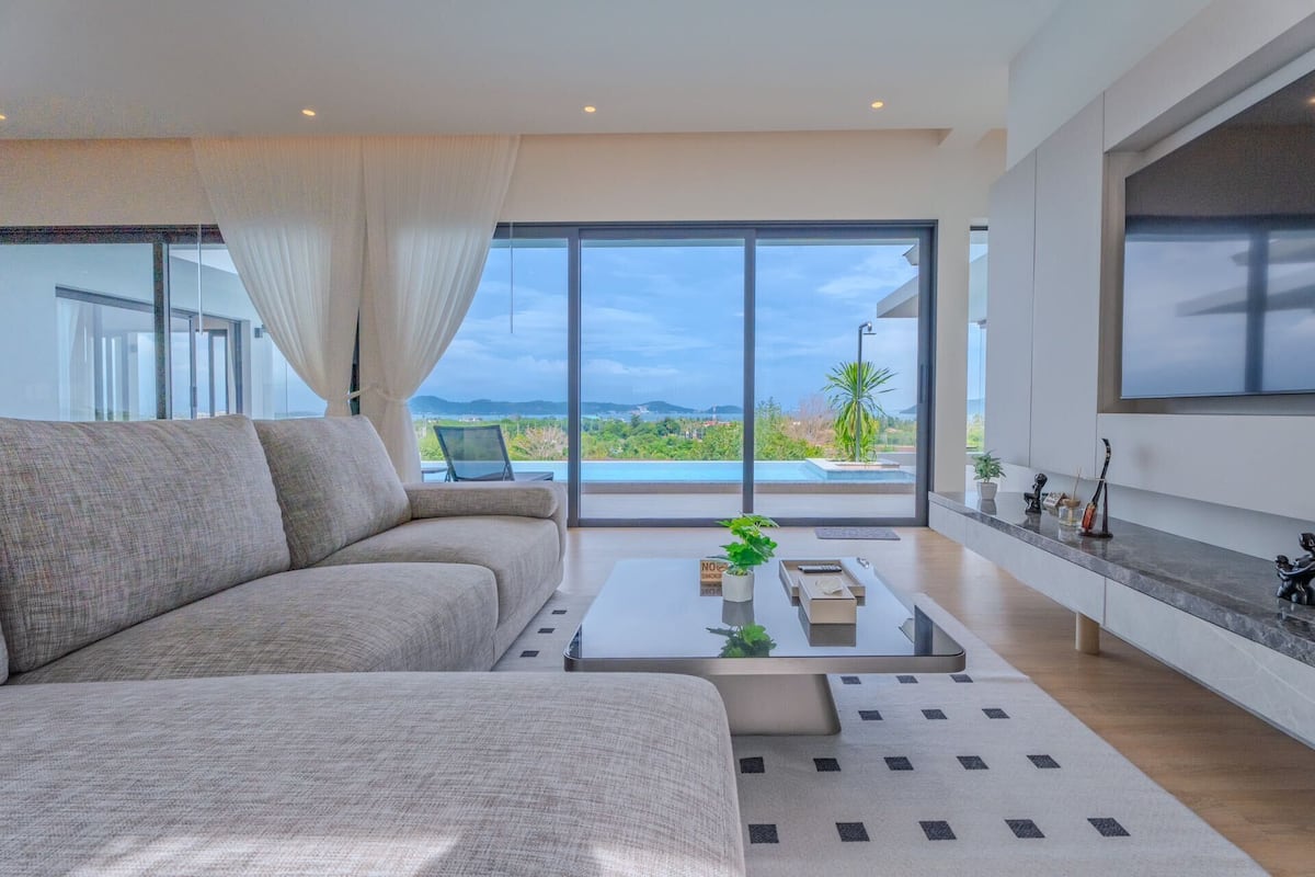 A modern living room with a large sofa, a coffee table, and a TV mounted on the wall.