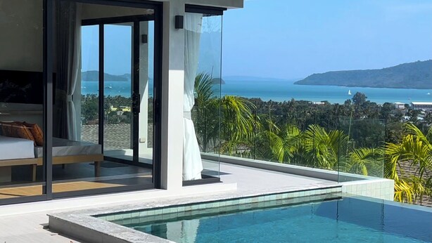 Uma piscina infinita moderna com vista clara para o mar e para a paisagem urbana.