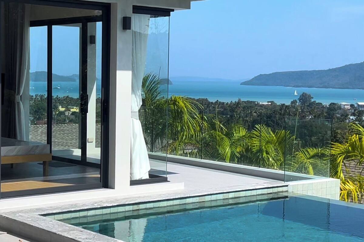 A modern infinity pool with a clear view of the sea and a cityscape.