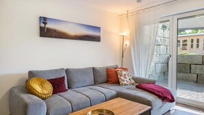 En moderne stue med en grå sofa, et træbord og et maleri på væggen.