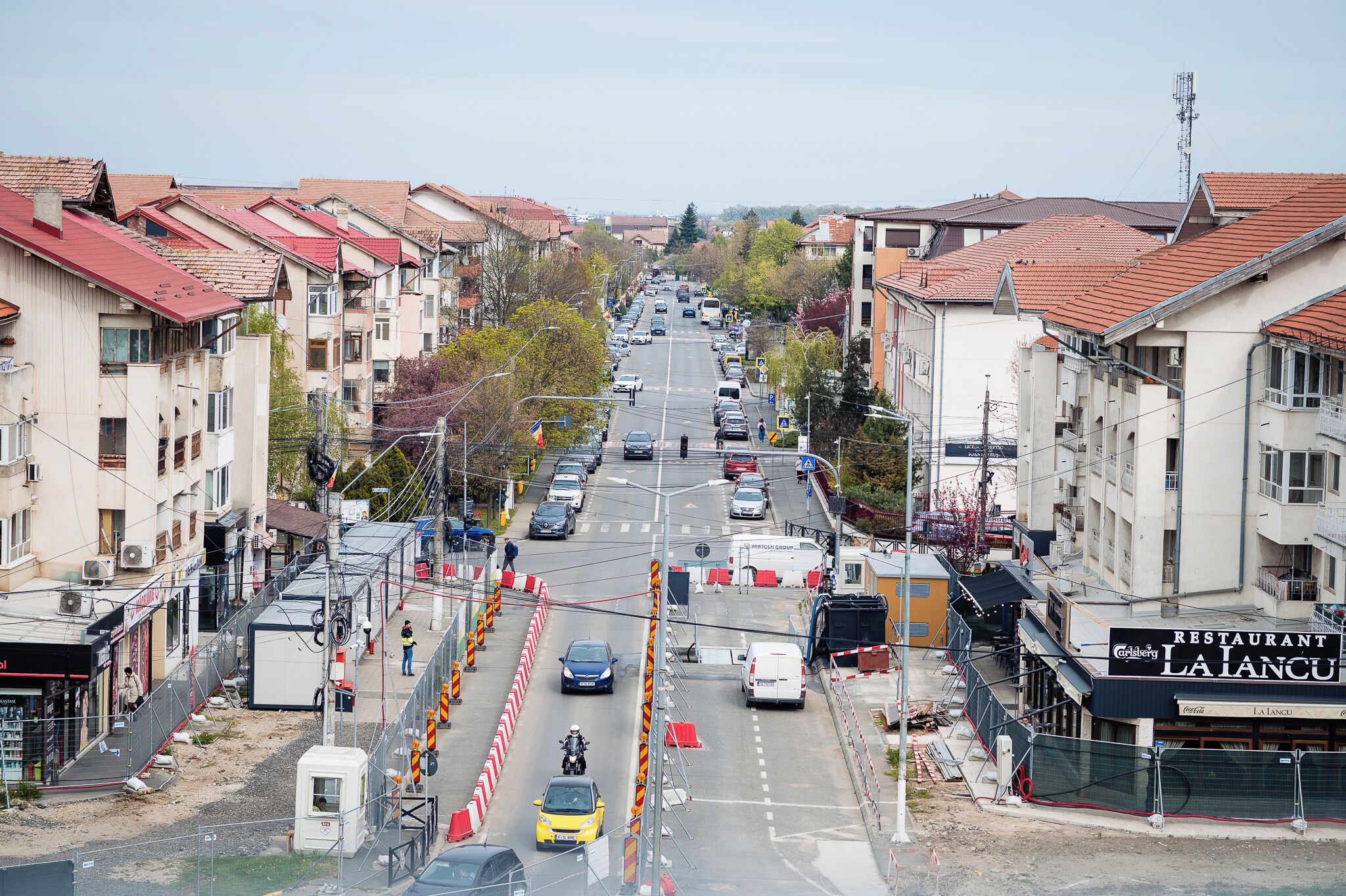 A street view with buildings, vehicles, and a pedestrian crossing.