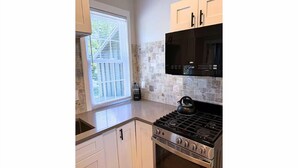 A kitchen with white cabinets, a black stove, and a microwave.
