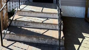 A house with a number '162' on the wall, a front door, and a staircase leading to the entrance.