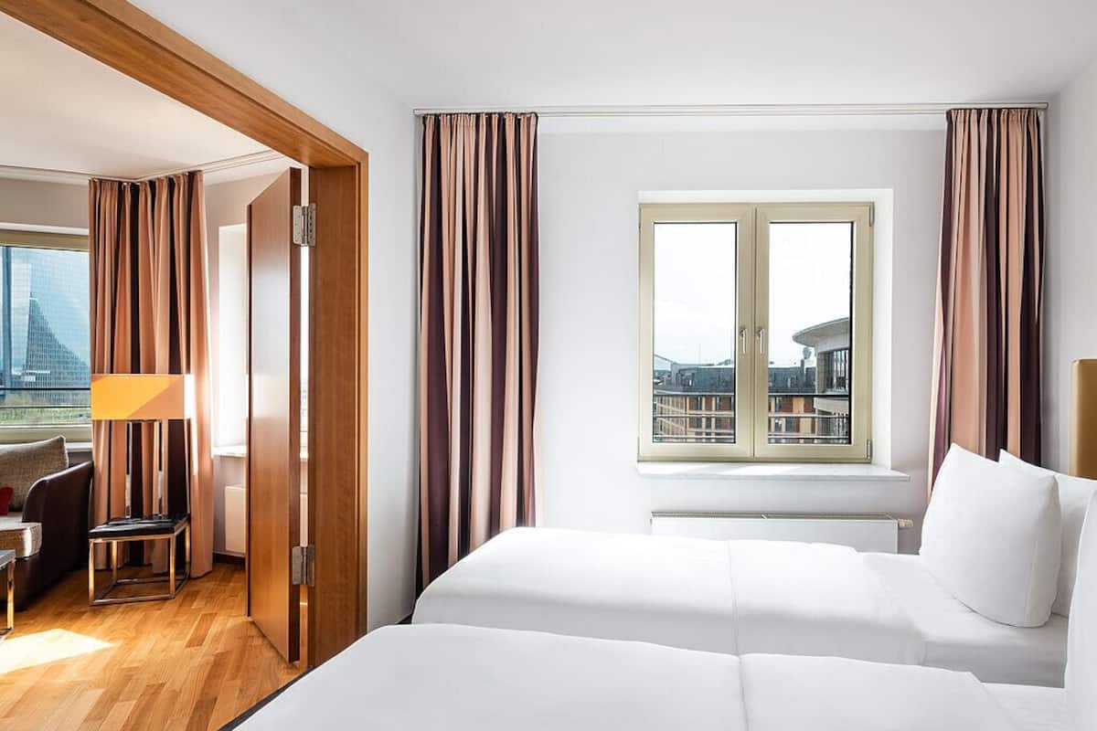Een hotelkamer met een bed, een bureau en uitzicht op een stadslandschap door een raam.