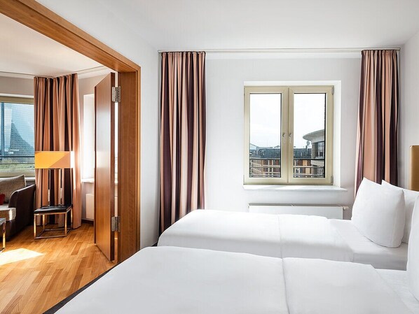 A hotel room with a bed, a desk, and a view of a cityscape through a window.