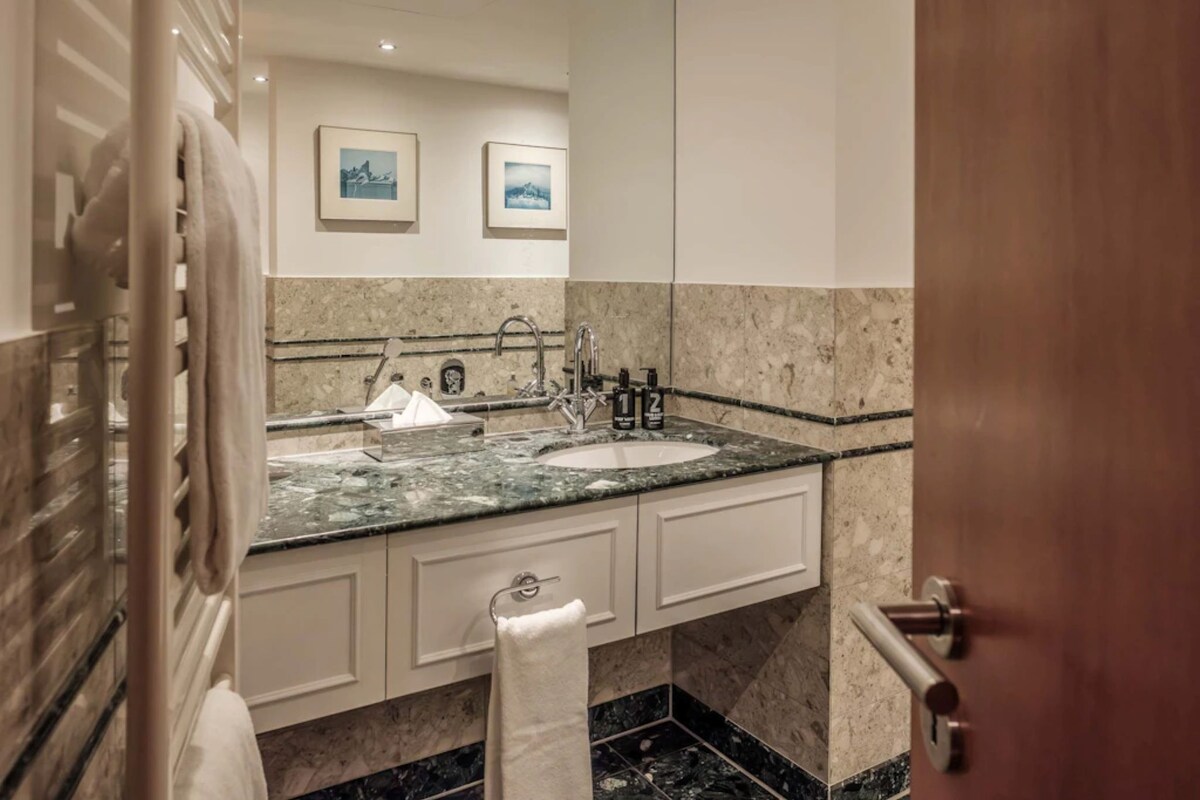 A bathroom with a marble sink, a towel rack, and framed pictures on the wall.