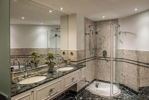 Un bagno moderno con due lavabi, una cabina doccia in vetro e uno specchio grande.