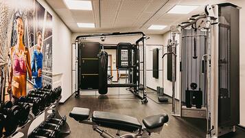 Ein Fitnessraum mit Gewichthebern, Bänken und einer Wand mit Motivationspostern.