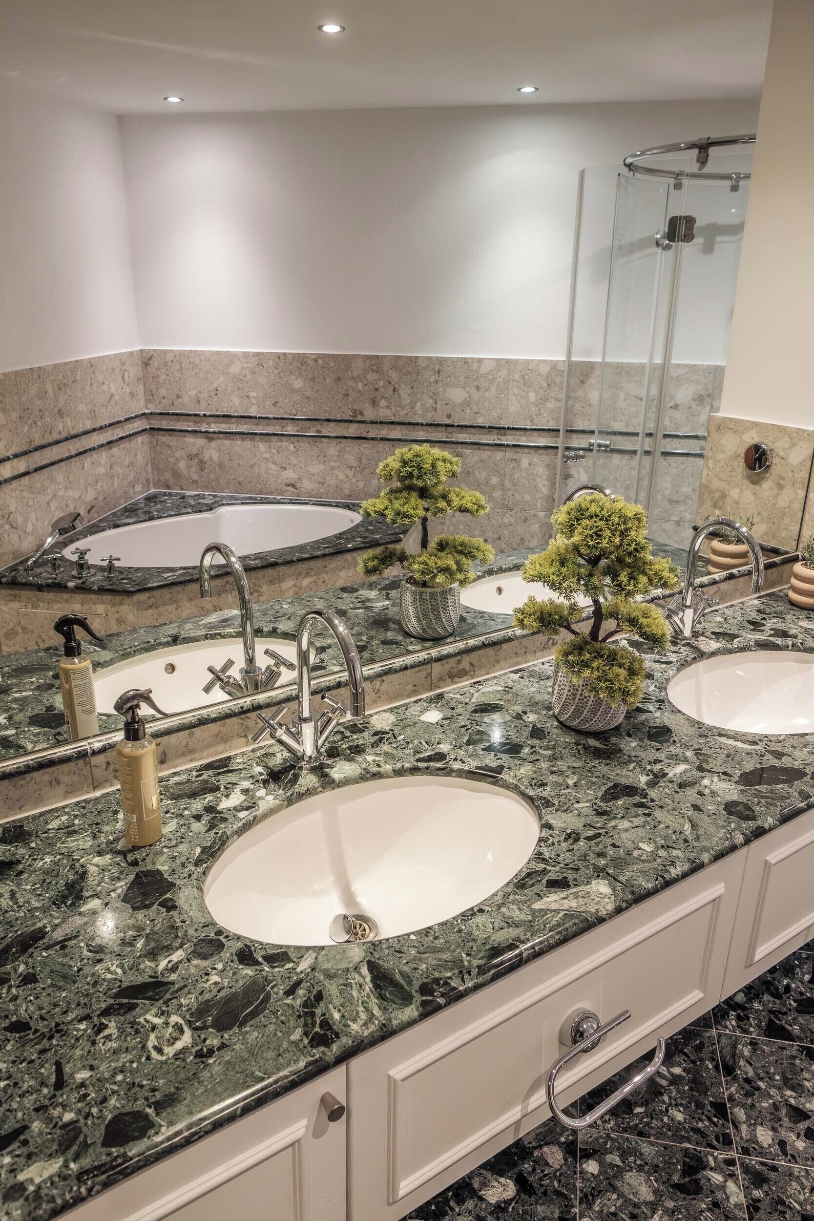 A bathroom with two sinks, a glass shower enclosure, and a large mirror.