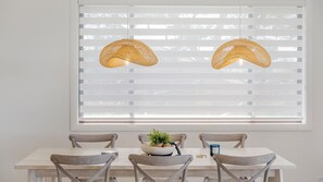 Un coin repas comprenant une table, des chaises et deux lampes en rotin suspendues au plafond.