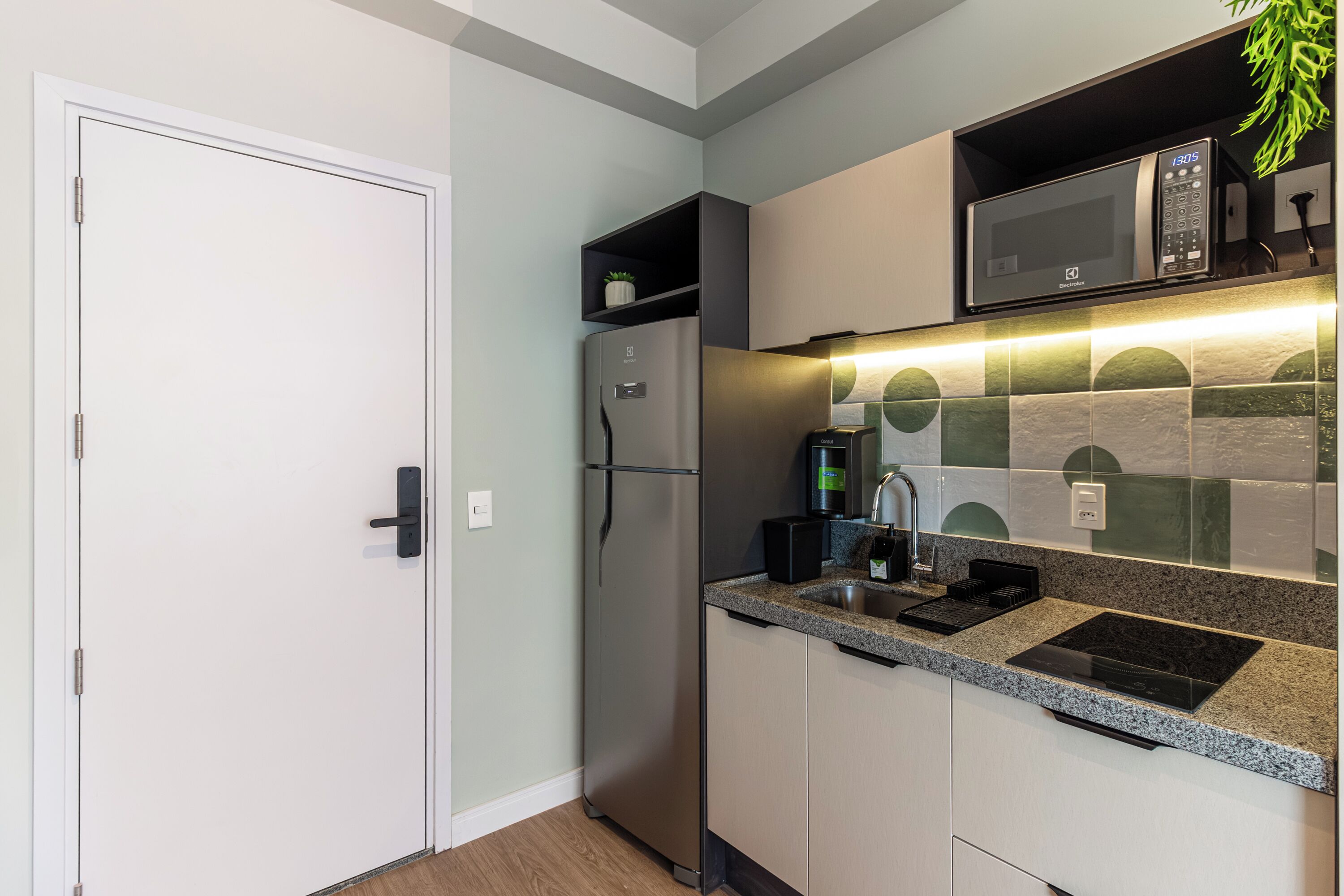 Een moderne keuken met een ingebouwde magnetron, een koffieapparaat en een spoelbak.