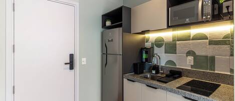 A modern kitchen with a built-in microwave, a coffee machine, and a sink.