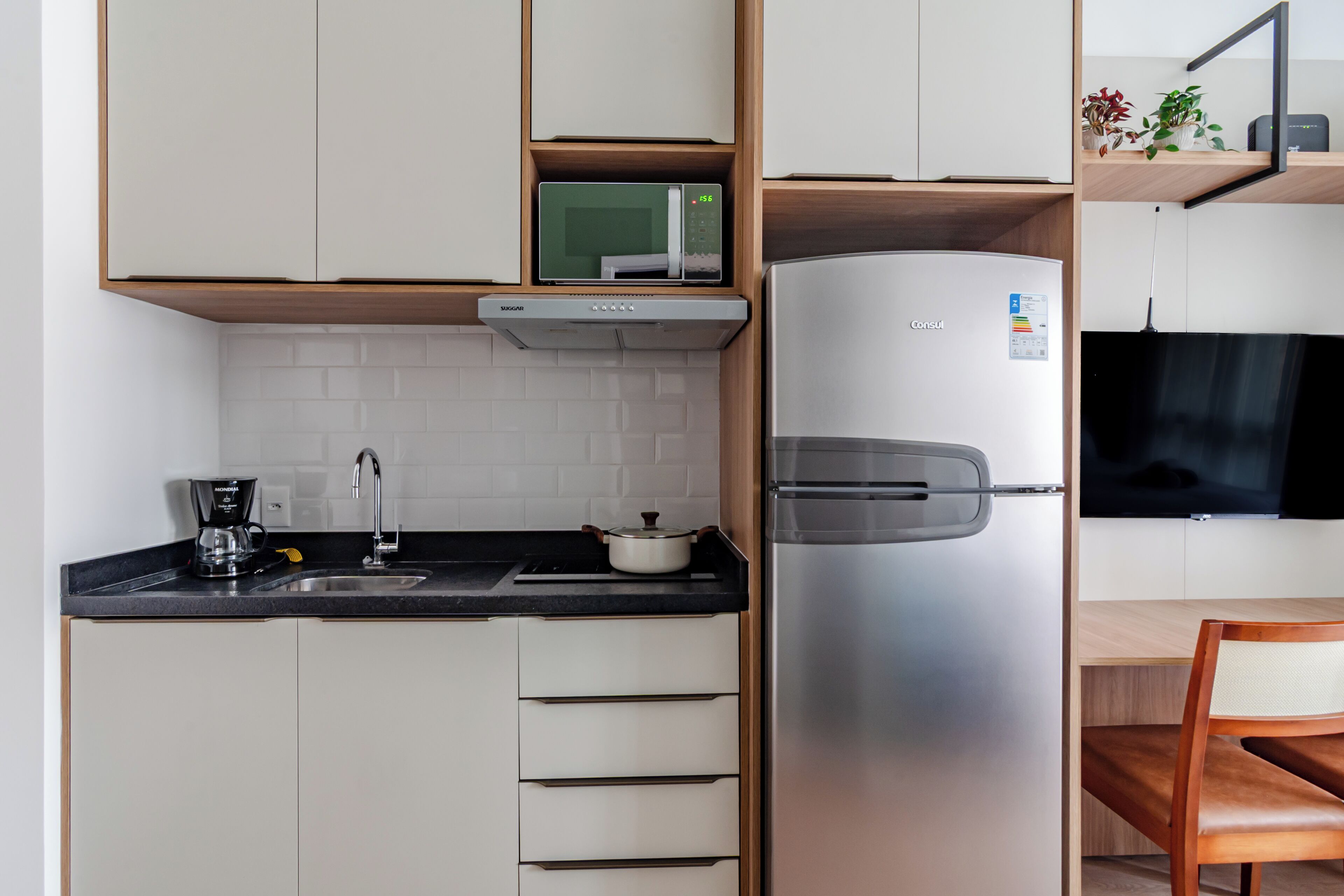 A compact kitchen with a built-in microwave, stainless steel refrigerator, and a coffee maker.