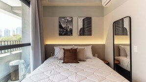 A hotel room with a large bed, a balcony, and two artworks on the wall. - 360 Essential Brooklin (São Paulo)