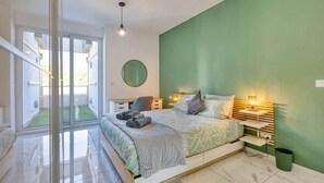 A modern bedroom with a large bed, a green accent wall, and a view through a glass door to an outdoor area. - The Green Haven in the Heart of St Julians (Saint Julian's)