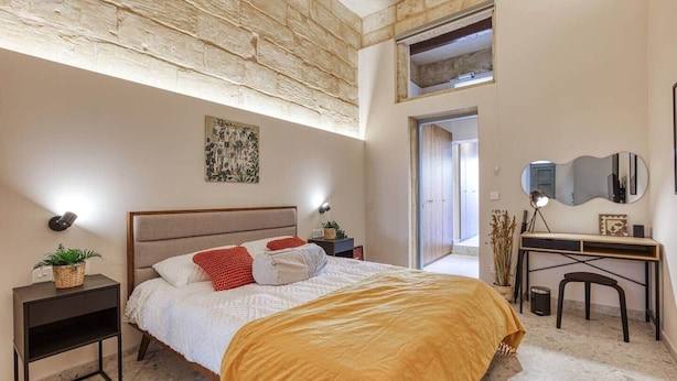 Una camera da letto con un letto, comodini, una scrivania e uno specchio.