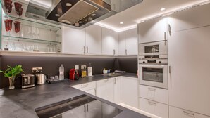 Een moderne keuken met een centraal eiland, een ingebouwde oven en een vitrinekast met glazen deuren.
