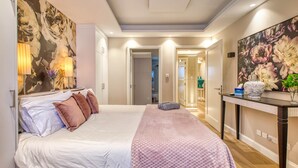 Een moderne slaapkamer met een groot bed, een consoletafel met een vaas en een spiegel.