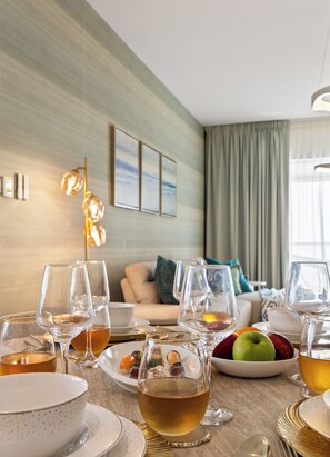 A dining area with a table set for a meal, including plates, glasses, and a bowl of fruit. - WYZ RENT|Salt&Sand Hamptons Glow 2BR SulafaMarina (Dubai)