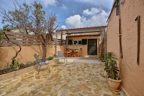 Un patio con pavimento in pietra, recinzione in legno e tavolo con sedie.