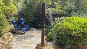 Un patio de piedra con sillas azules y una fuente de agua.