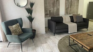 Un salon moderne avec un fauteuil gris, un canapé foncé et une table basse.