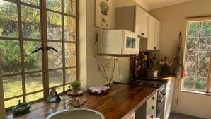A kitchen with a large window, wooden countertop, and a sink. - Victorian Style Cottage in Nyanga - 2096 (Juliasdale)