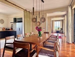 A spacious dining area with a long wooden table, multiple chairs, and a vase of flowers.