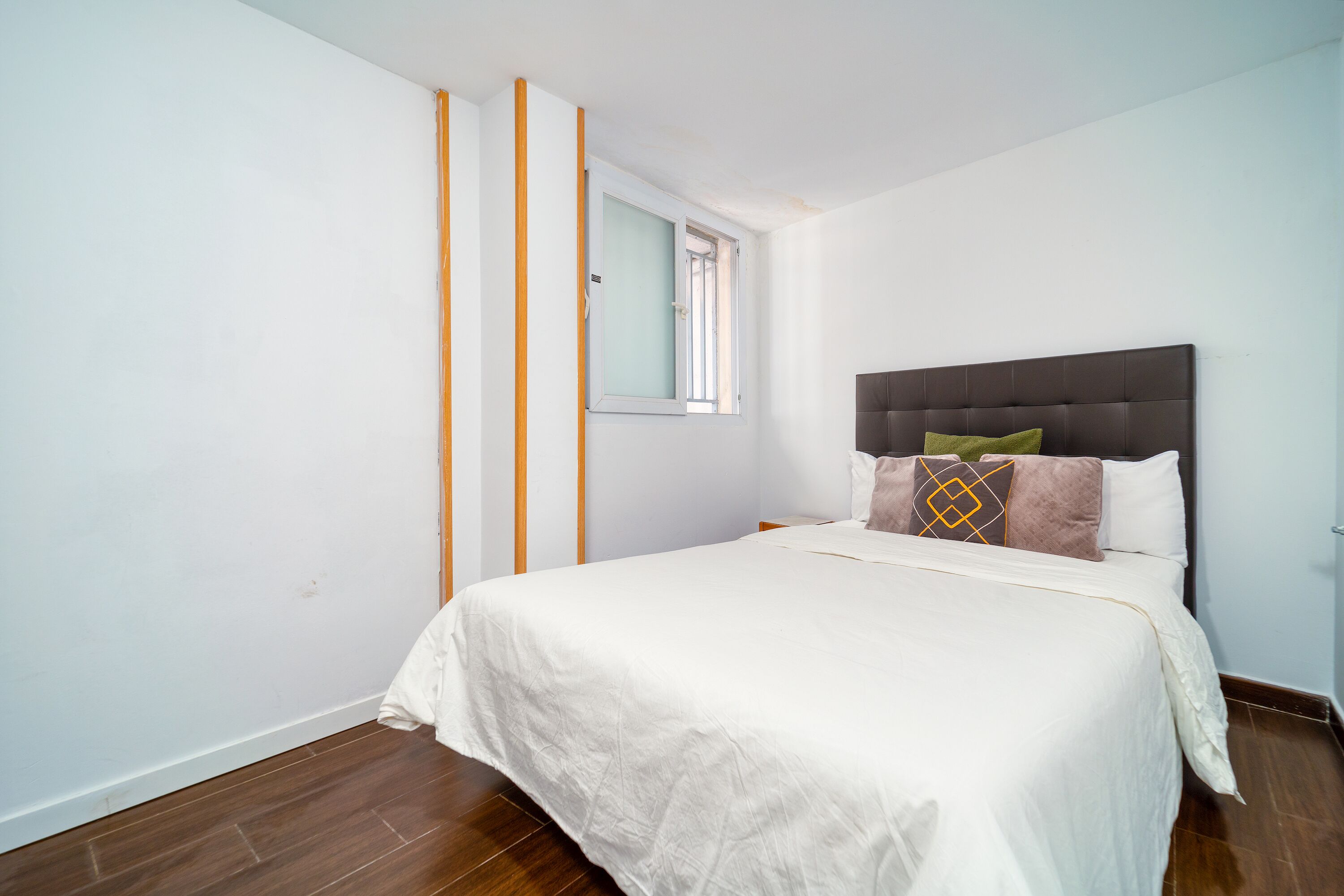 A bedroom with a bed, a window, and a door.