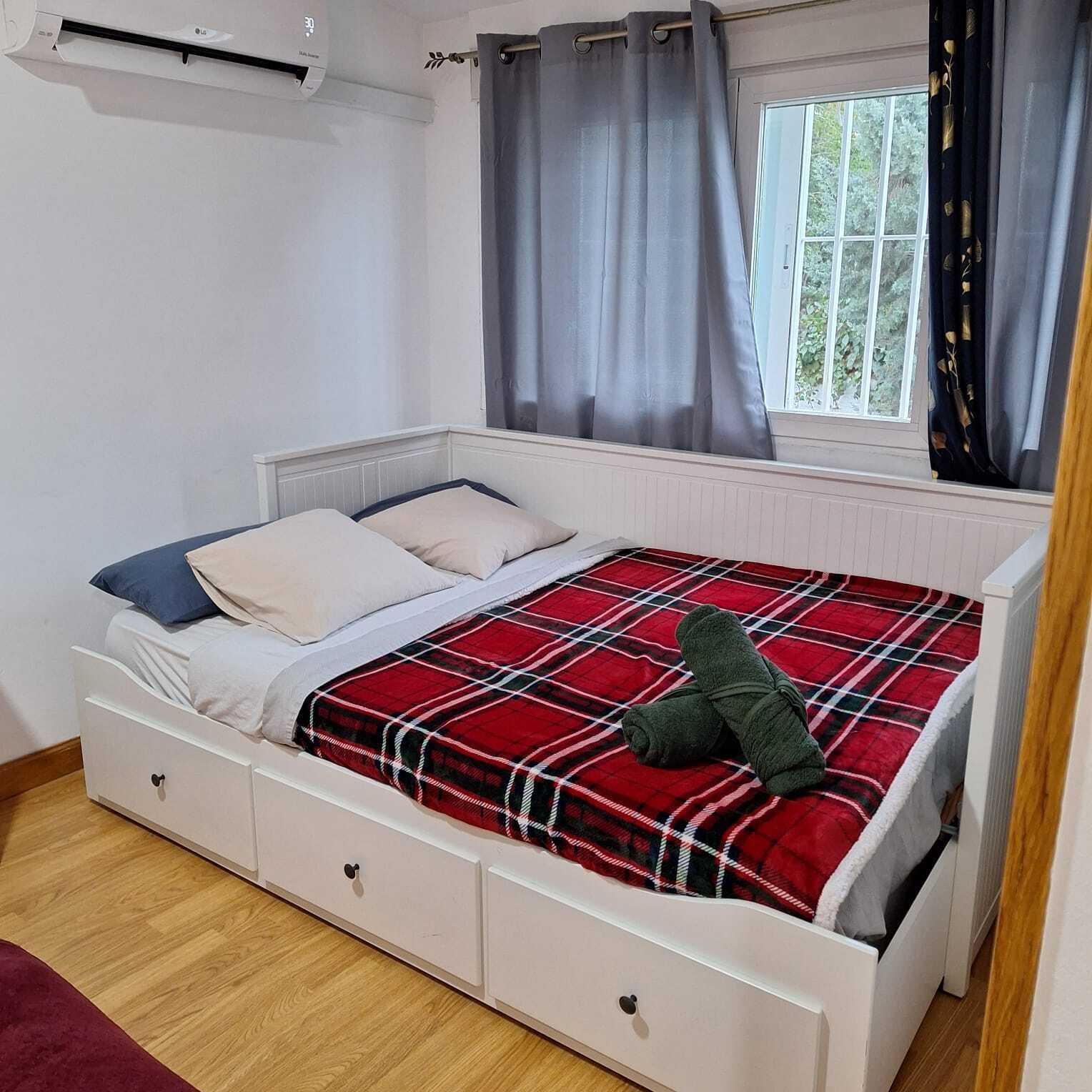Un dormitorio con cama, ventana y aire acondicionado.