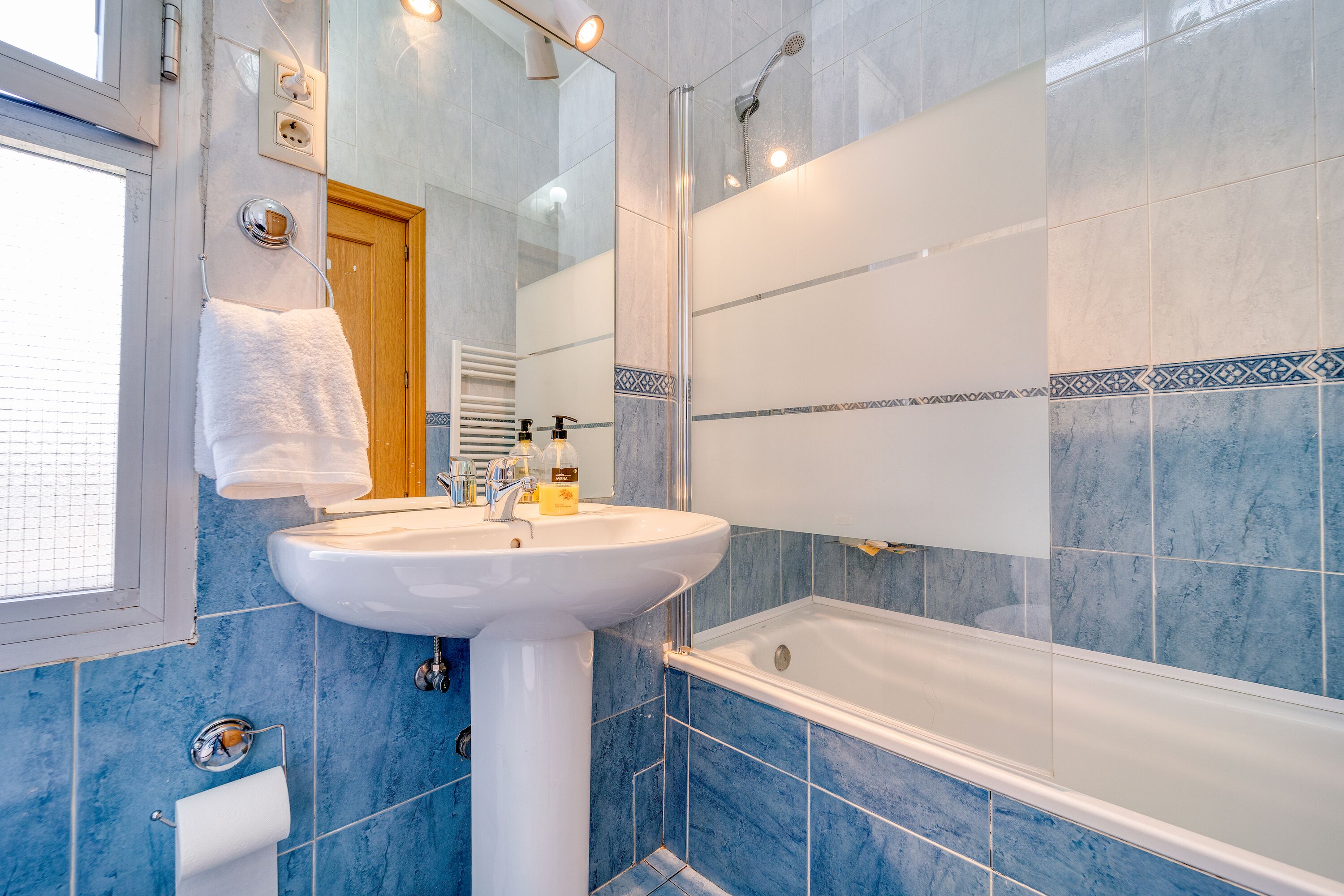A bathroom with a sink, mirror, and bathtub.