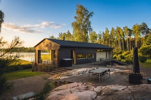 A cabin with a deck, a hot tub, and a view of a lake.