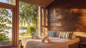 Ein Schlafzimmer mit einem großen Bett, Holzwänden und Blick auf einen See.