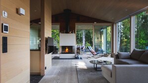 Ein modernes Interieur mit Kamin, Holzwänden und einer Sitzecke mit Blick ins Freie.