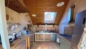 A compact kitchen with wooden cabinets, a microwave, a stove, and a refrigerator.