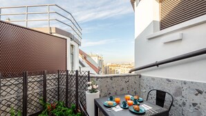 A rooftop terrace with a table set for breakfast, including croissants and orange juice, surrounded by a metal fence and potted plants. - Luxury Penthouse 2 Bedooms 2 Bathrooms (Milan)