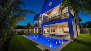 A modern two-story house with a swimming pool, a balcony, and a well-maintained lawn. - Elegance~Gorgeous! Arcade!~ Heated pool/spa~North End! (Anna Maria)