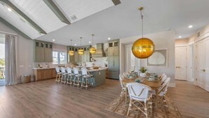 A spacious kitchen with a central island, pendant lighting, and a dining area with a round table and chairs. - Elegance~Gorgeous! Arcade!~ Heated pool/spa~North End! (Anna Maria)