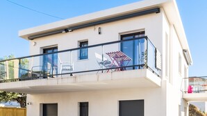 Een modern gebouw met twee verdiepingen, een balkon, een plat dak en een heldere lucht.