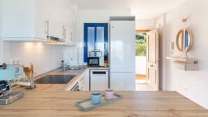 Una cocina moderna con armarios blancos, una puerta azul, un refrigerador blanco y una encimera de madera.