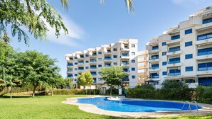 Un edificio residencial con piscina, rodeado de vegetación y árboles.