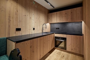 Una cocina moderna con armarios de madera, encimera negra y electrodomésticos integrados.